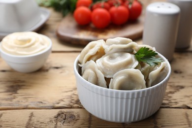 Tasty dumplings in bowl on wooden table