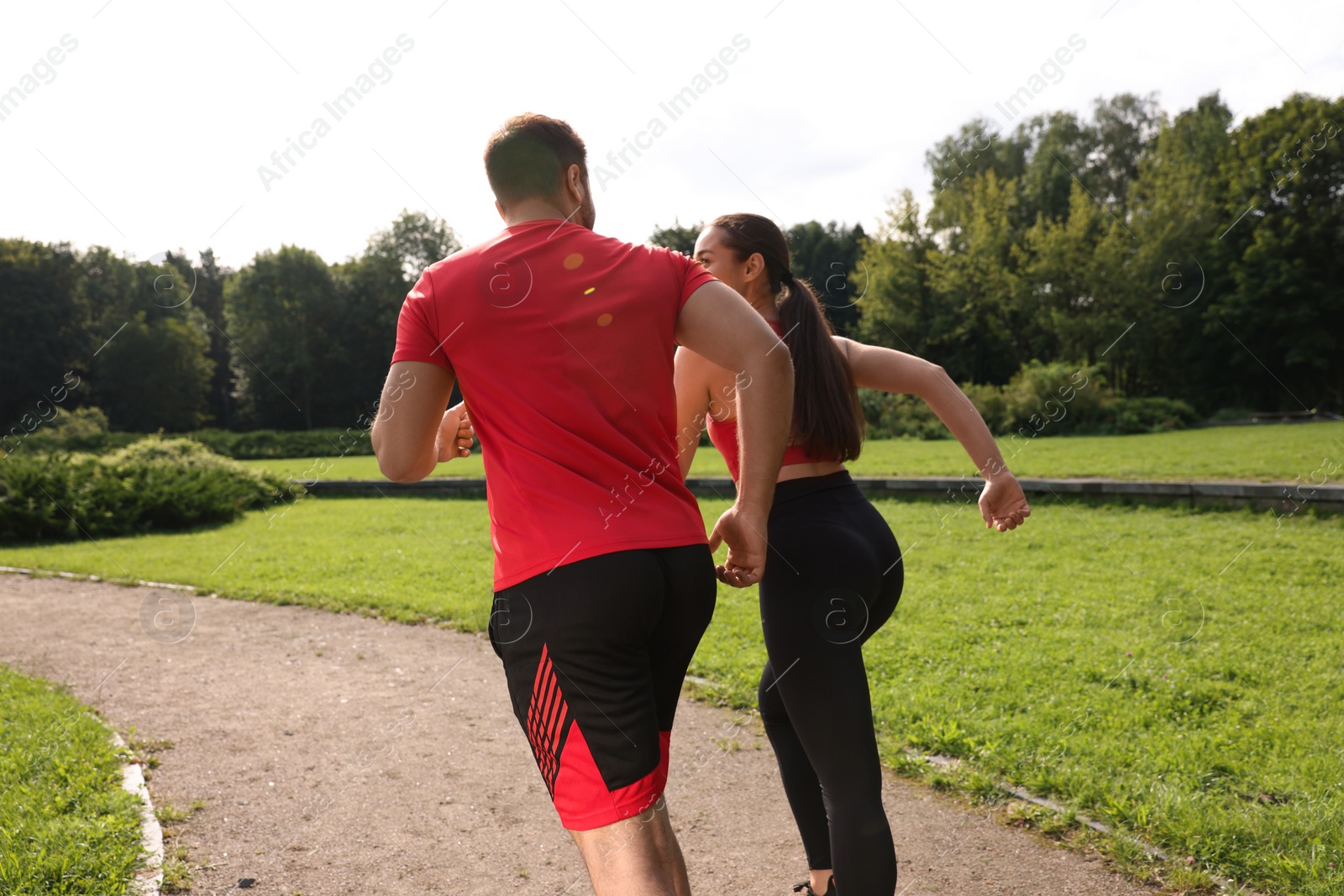 Photo of Healthy lifestyle. Couple running in park on sunny day, back view