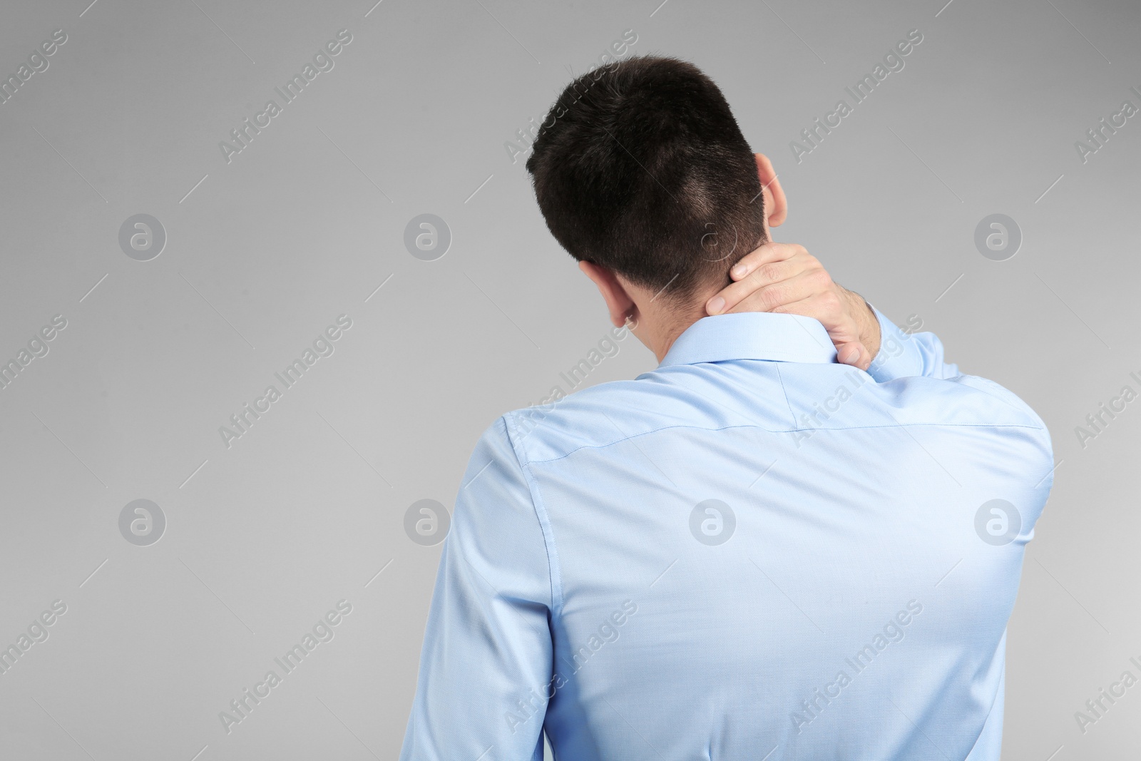 Photo of Young man suffering from neck pain on light background