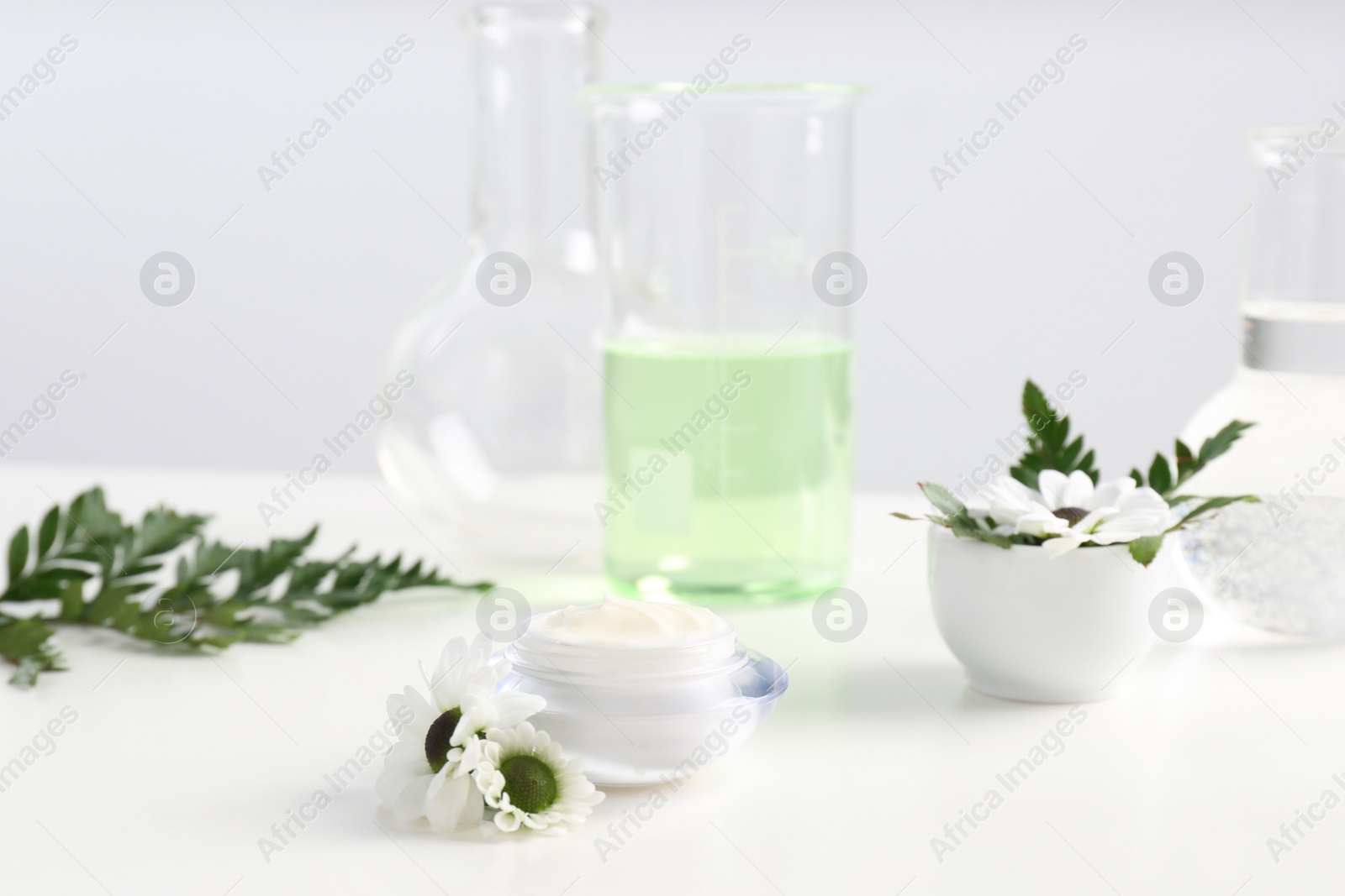 Photo of Skin care product, ingredients and laboratory glassware on table. Dermatology research