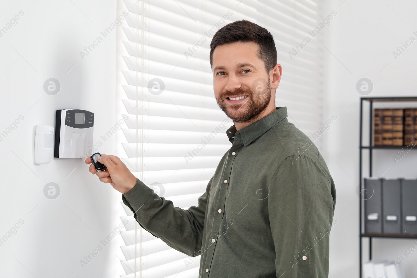 Photo of Home security system. Man using alarm key fob indoors