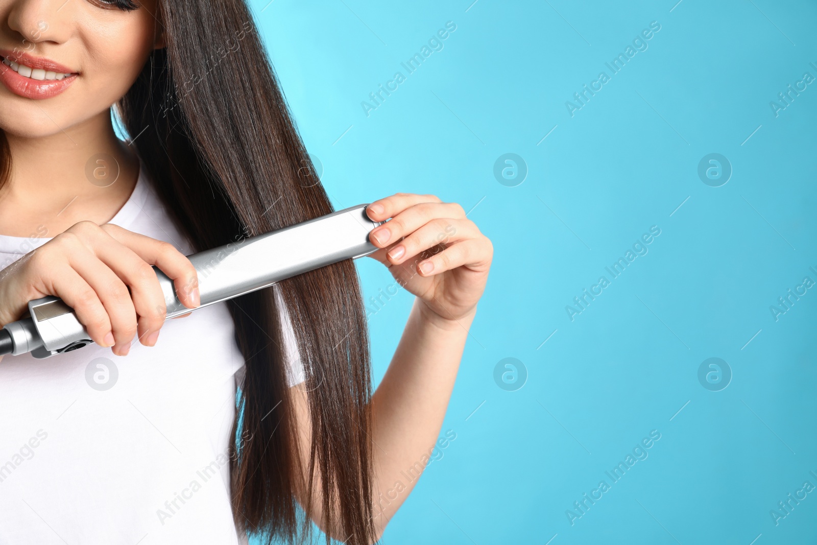 Photo of Happy woman using hair iron on color background, closeup. Space for text