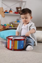 Photo of Cute little boy playing toy drum at home