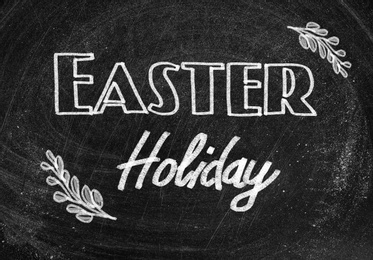 Image of Text Easter Holiday and drawings on black chalkboard. School break 
