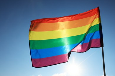 Photo of Bright LGBT flag fluttering against blue sky