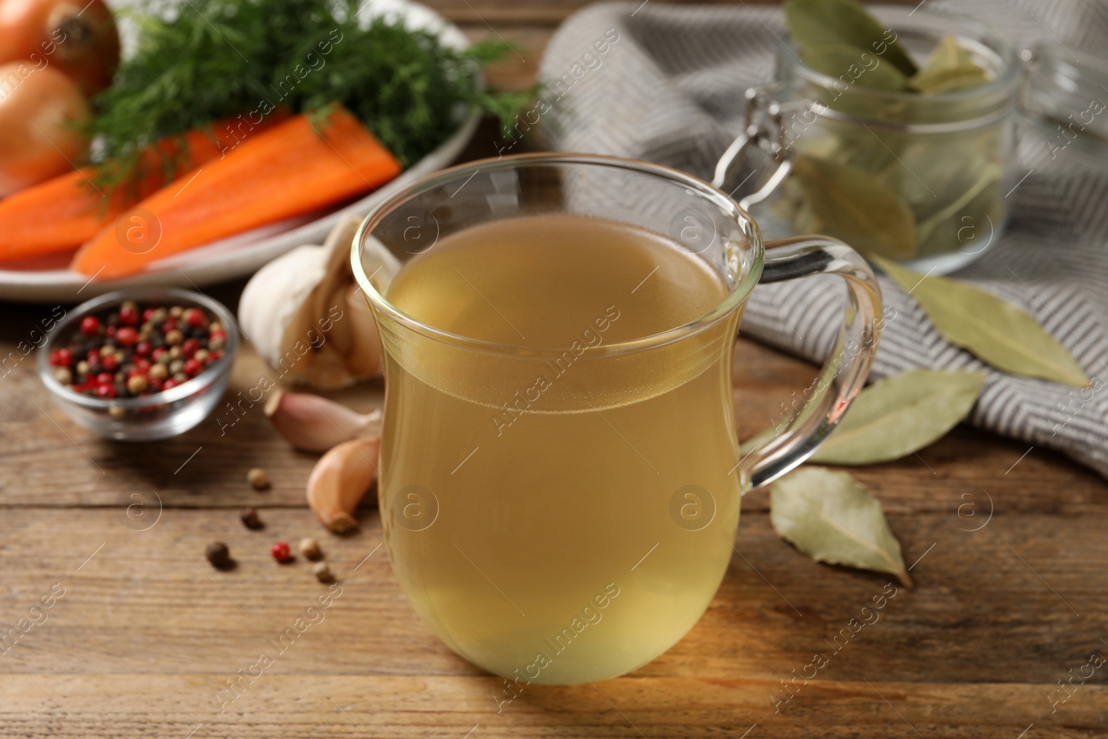 Photo of Hot delicious bouillon in glass cup on wooden table