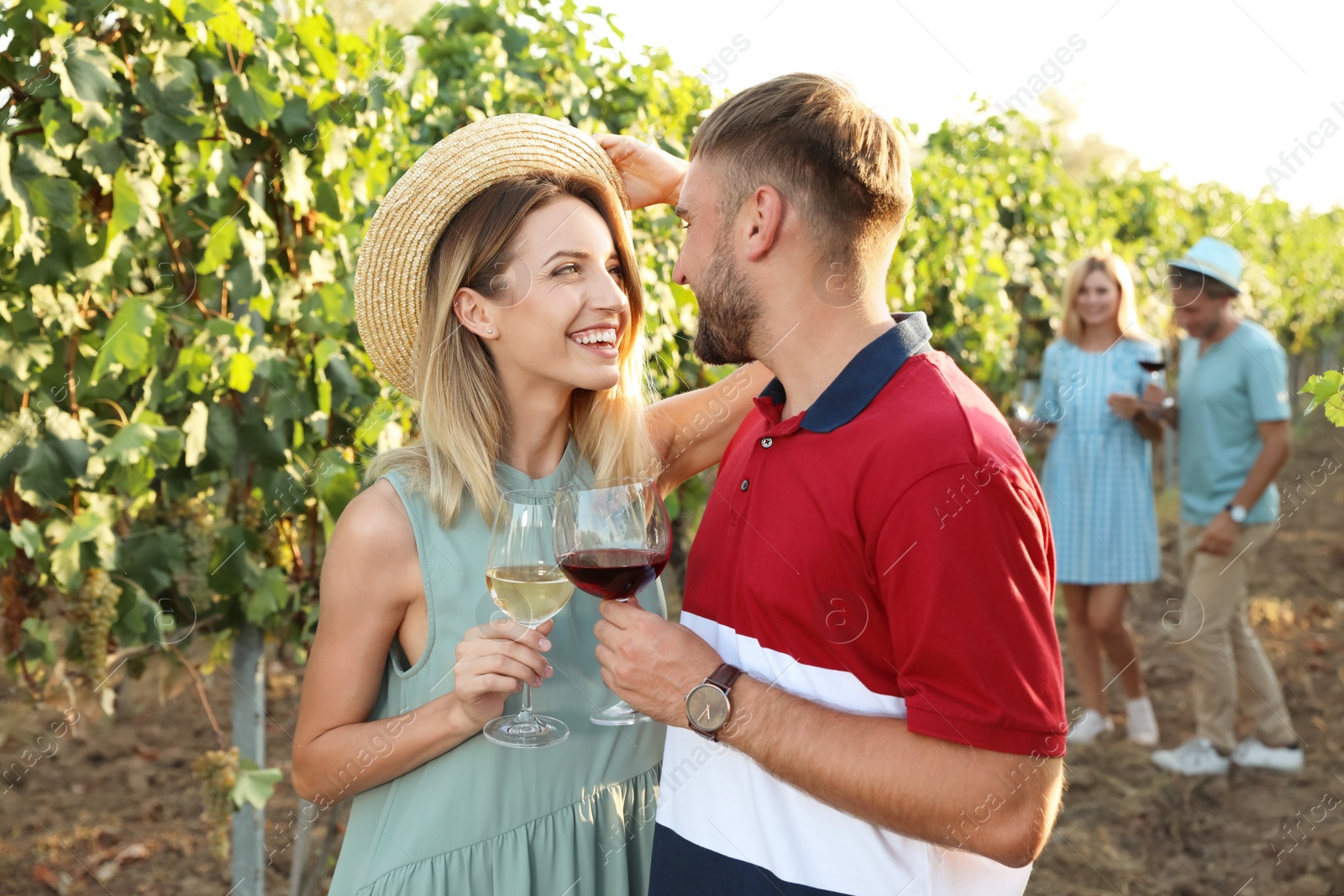 Photo of Romantic couple holding glasses of wine at vineyard