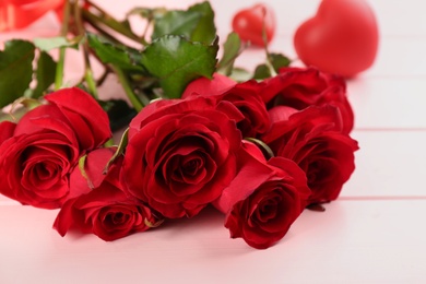Photo of Beautiful red roses on pink table, closeup. Valentine's Day celebration
