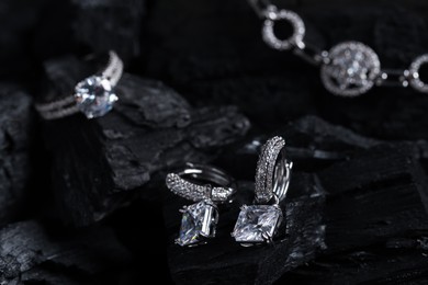 Photo of Luxury jewelry. Stylish presentation of elegant earrings on coal, closeup