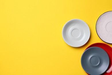 Photo of Clean ceramic plates on yellow background, flat lay. Space for text