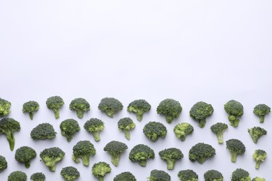 Many fresh green broccoli pieces on white background, flat lay. Space for text