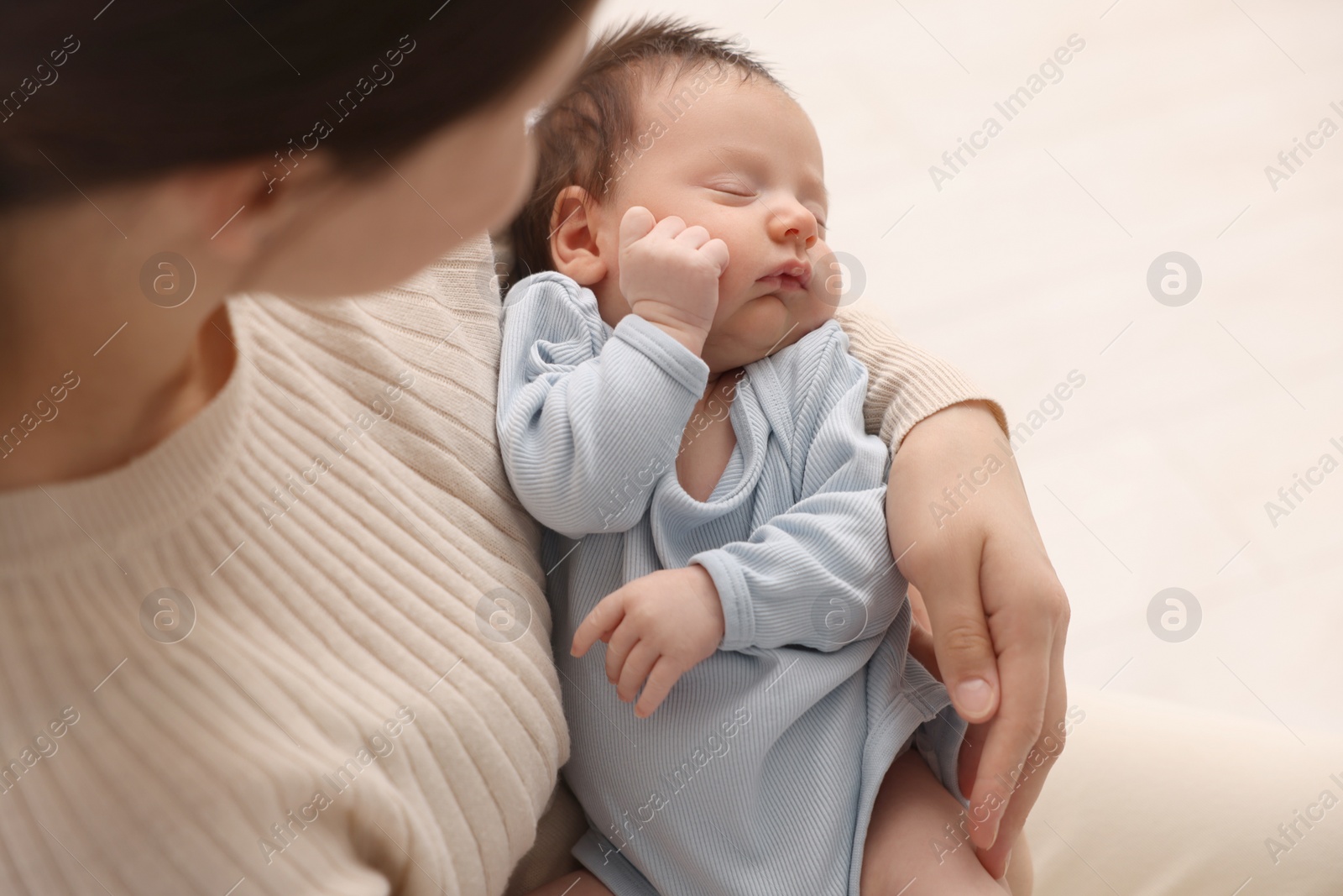Photo of Mother with her sleeping newborn baby on light background, closeup