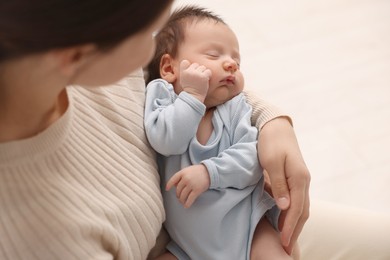 Mother with her sleeping newborn baby on light background, closeup