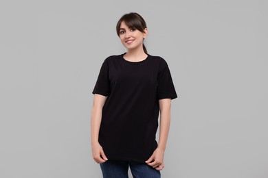 Smiling woman in stylish black t-shirt on light grey background