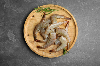 Photo of Fresh raw shrimps with rosemary on grey table, top view