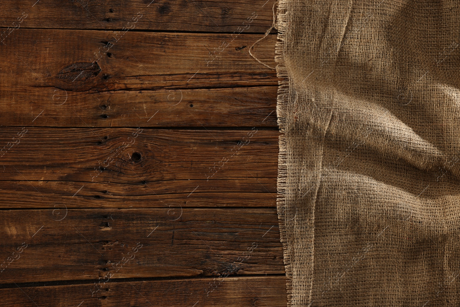 Photo of Burlap fabric on wooden table, top view. Space for text