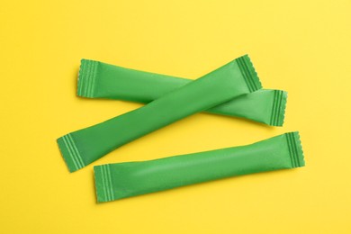 Photo of Green sticks of sugar on yellow background, flat lay