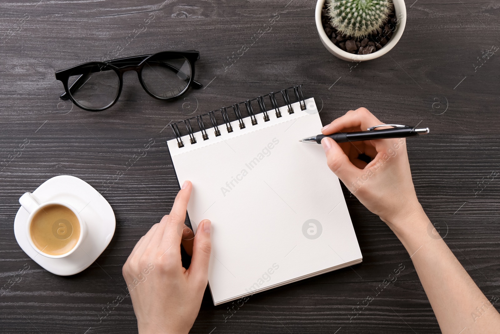 Photo of Woman with notebook and pen at grey wooden table, top view. Space for text