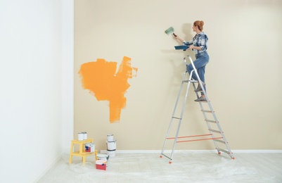 Woman painting wall indoors, space for text. Home repair