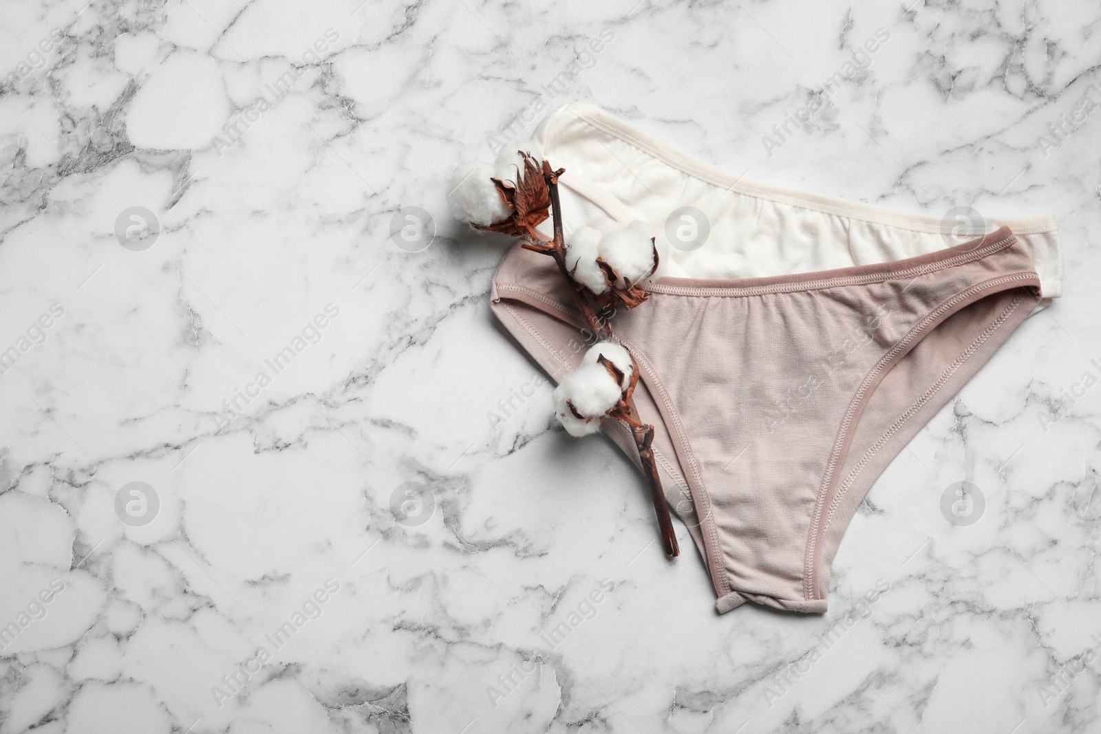 Photo of Women's underwear and cotton flowers on marble background, flat lay. Space for text