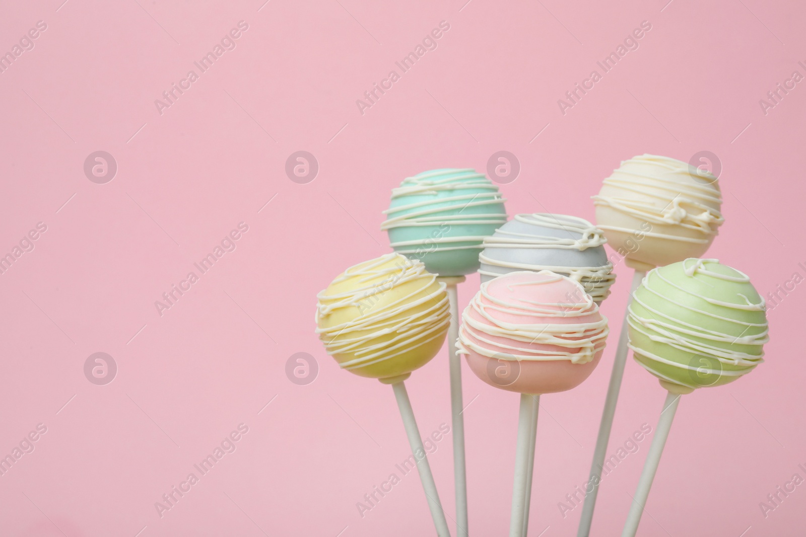 Photo of Sweet colorful cake pops on pink background