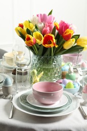 Photo of Easter celebration. Festive table setting with beautiful flowers and painted eggs