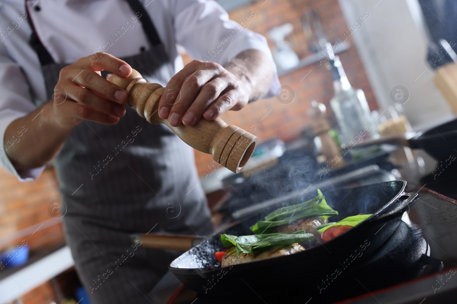 Photo of Professional chef cooking meat on stove in restaurant kitchen, closeup