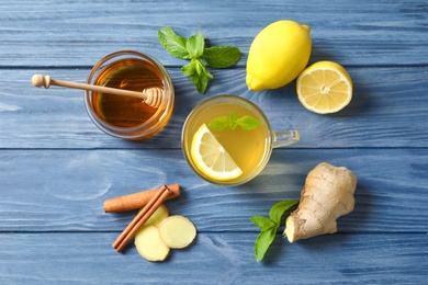 Photo of Cup with hot tea, lemon and ginger for cold on wooden table, top view