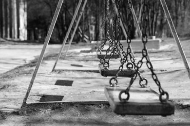 Photo of Wooden swings in park, space for text. Black and white effect