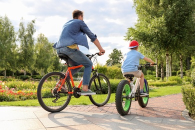 Photo of Dad and son riding modern bicycles outdoors