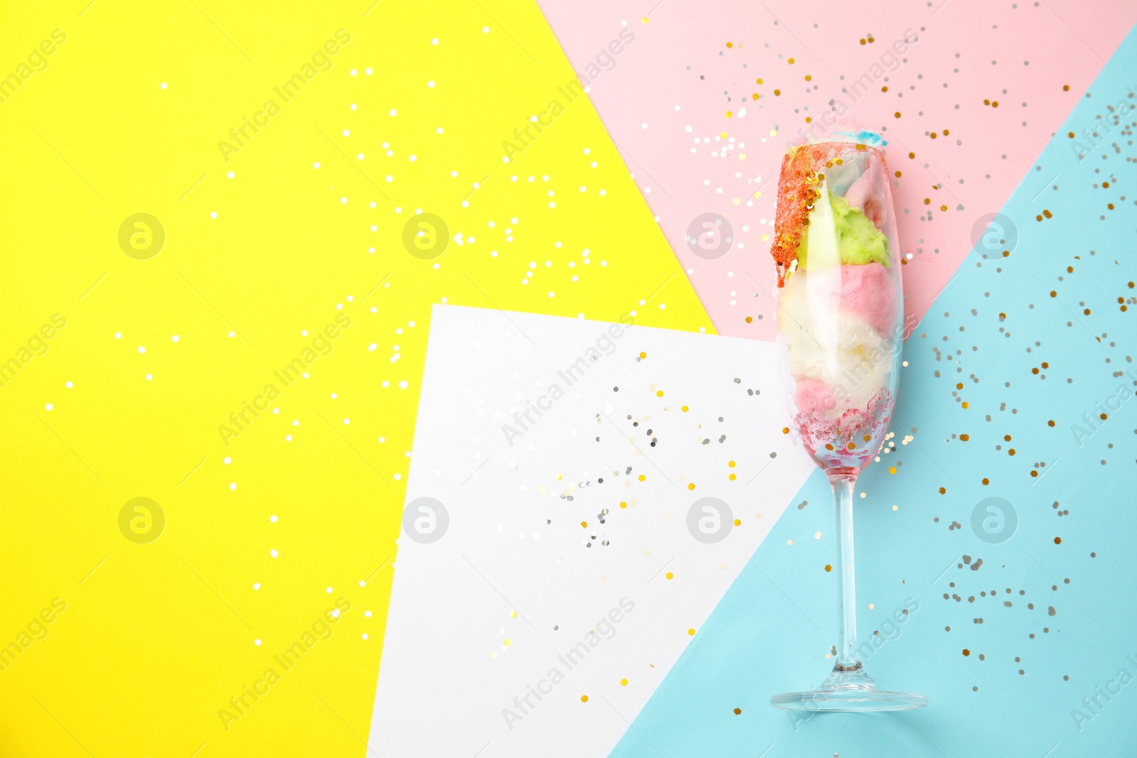 Photo of Glass with cotton candy on color background, top view. Space for text