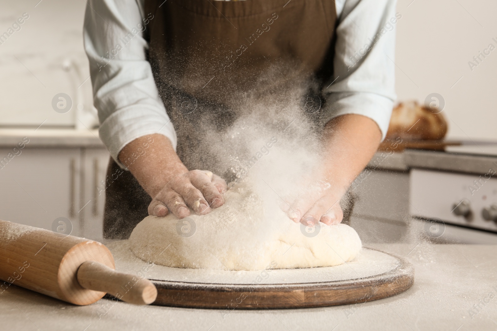 Photo of Female baker preparing bread dough at table, closeup