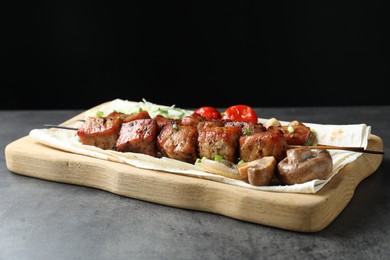 Photo of Delicious shish kebabs with vegetables and lavash on grey table