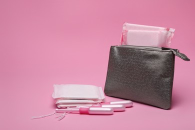 Photo of Silver bag, menstrual pads and tampons on pink background