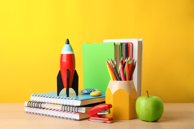 Bright toy rocket and school supplies on wooden table