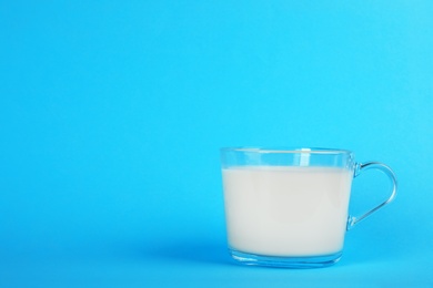 Photo of Glass cup with fresh milk on color background. Space for text