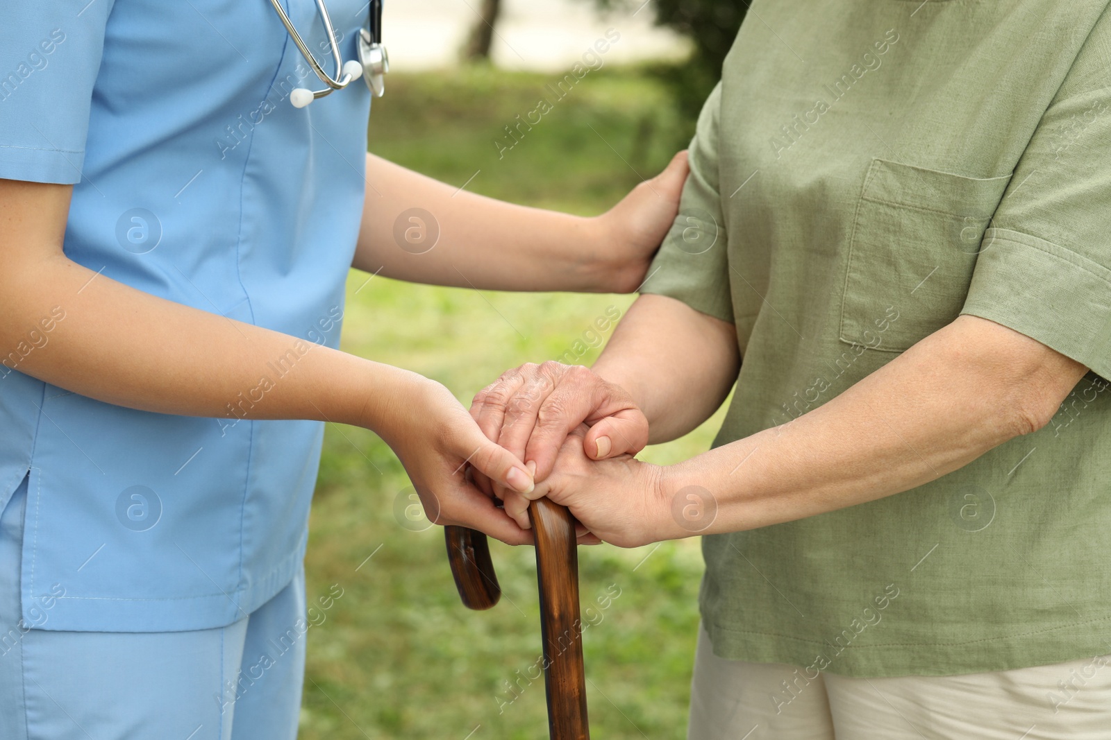 Photo of Elderly woman with walking cane and female caregiver outdoors, closeup