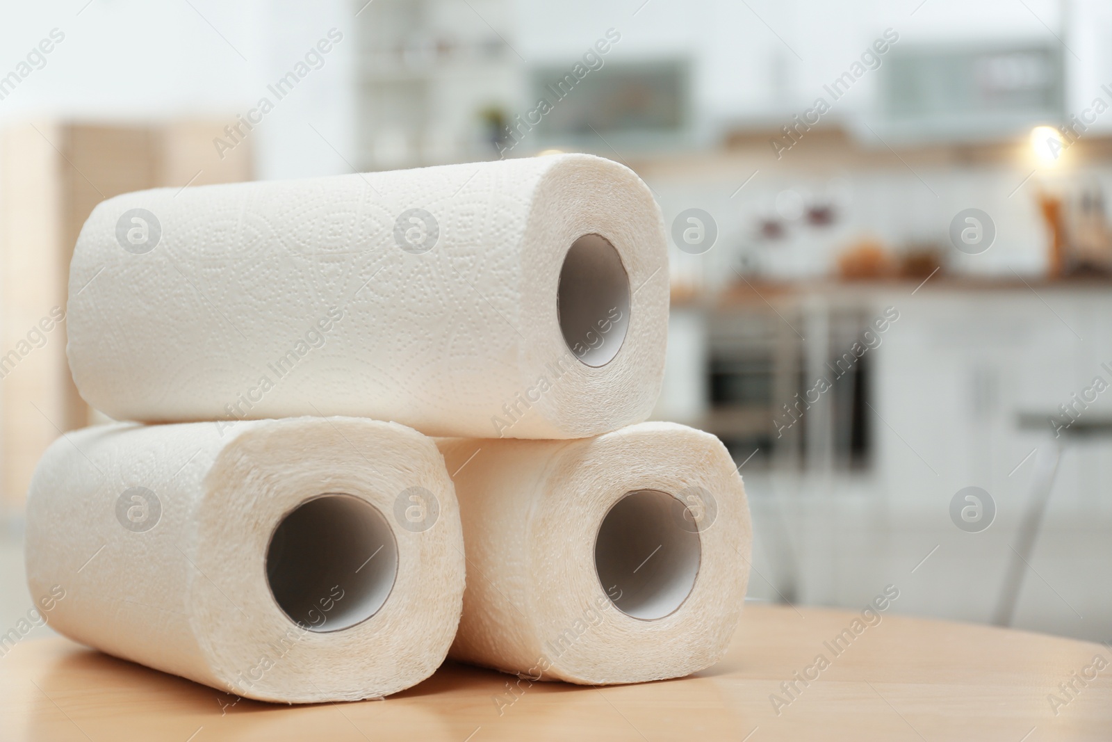 Photo of Rolls of paper towels on table in kitchen, space for text