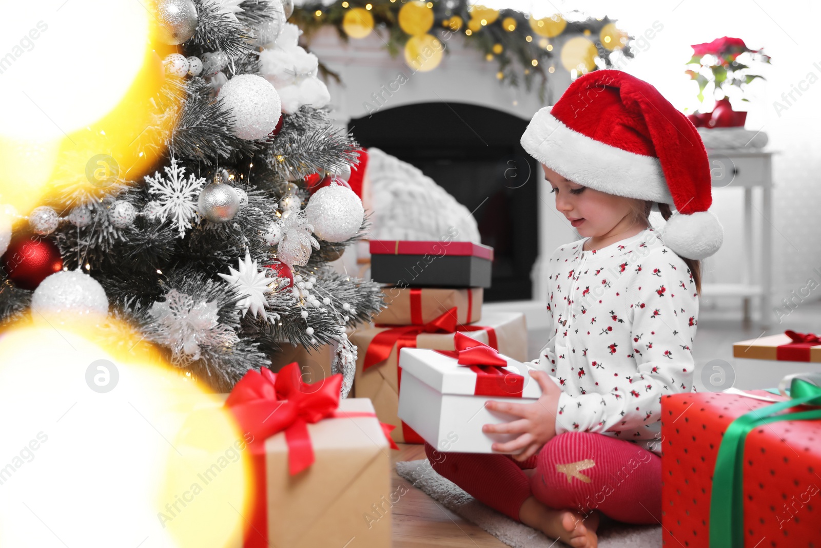 Photo of Cute little girl with Christmas gift on floor at home