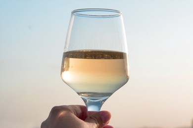 Photo of Woman holding glass of tasty wine against sky, closeup