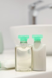 Photo of Mini bottles of cosmetic products on white countertop in bathroom