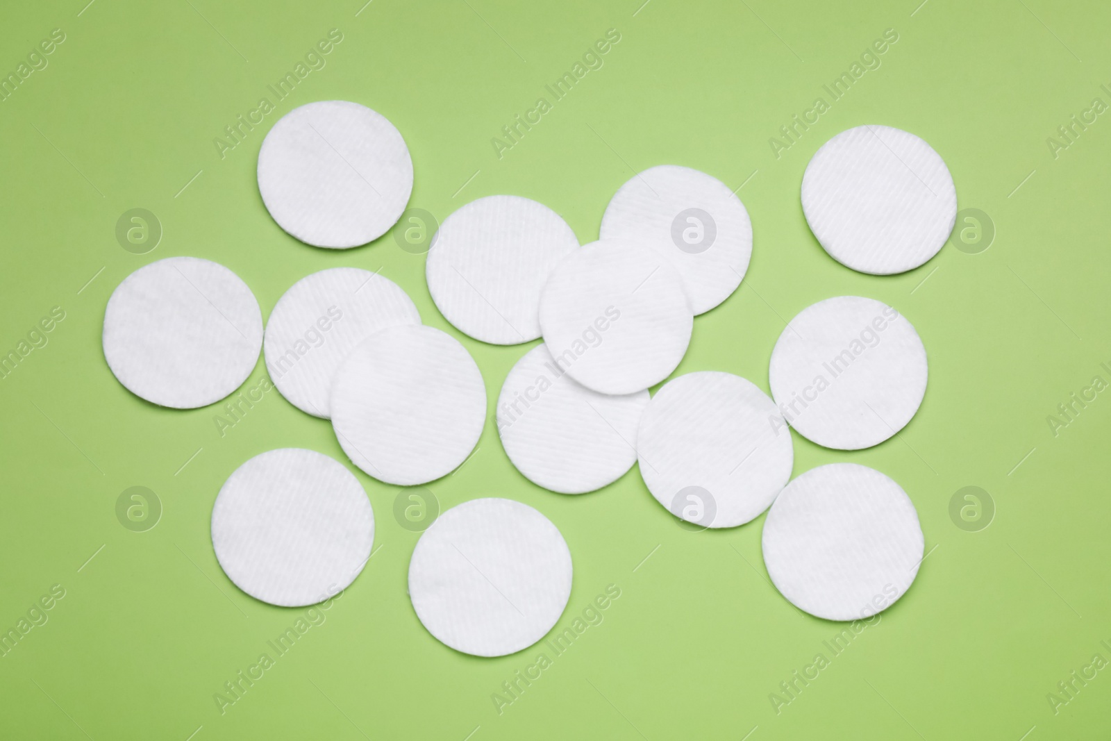 Photo of Many cotton pads on green background, flat lay
