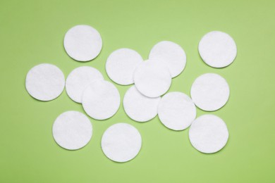 Many cotton pads on green background, flat lay