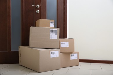 Photo of Stacked parcels near door on floor, space for text. Delivery service