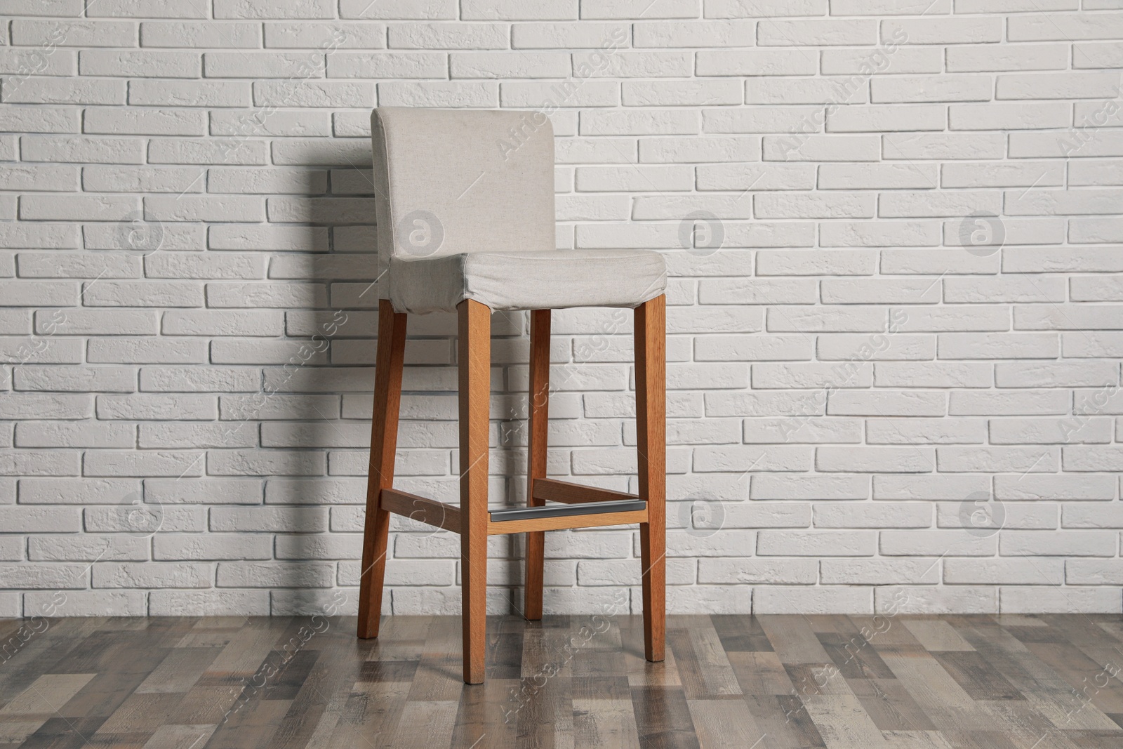 Photo of Stylish bar stool near white brick wall indoors