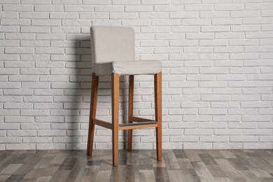 Photo of Stylish bar stool near white brick wall indoors