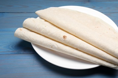 Photo of Delicious folded Armenian lavash on light blue wooden table, closeup