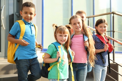 Photo of Cute little children with backpacks outdoors. Elementary school