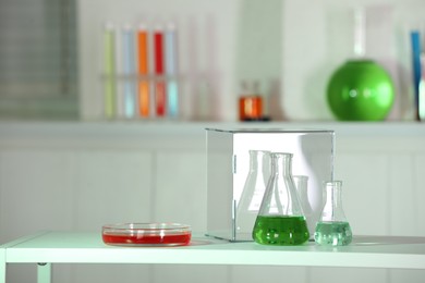 Laboratory analysis. Glass flasks and Petri dish with liquids on white table indoors. Space for text