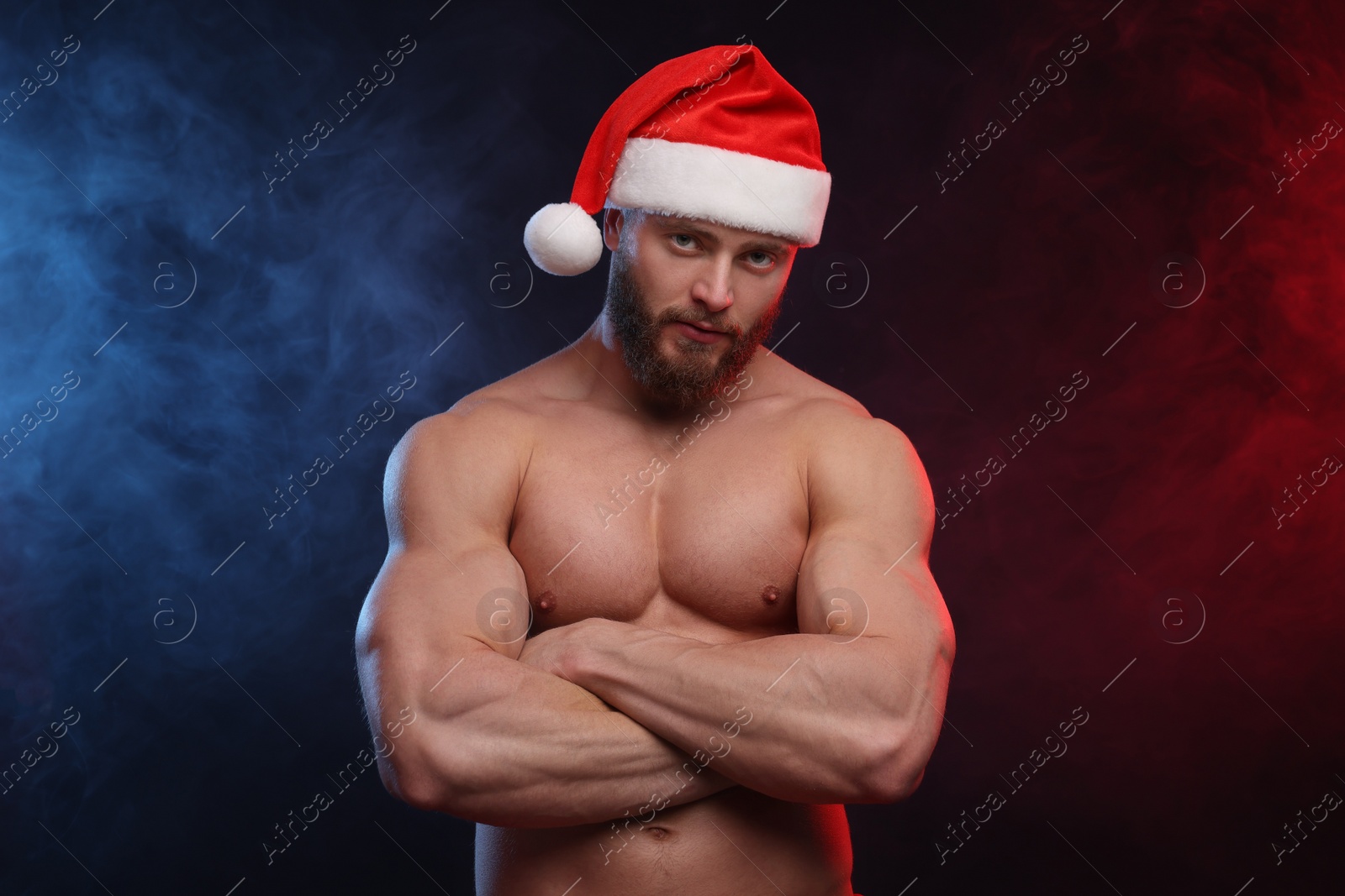 Photo of Attractive young man with muscular body in Santa hat on black background